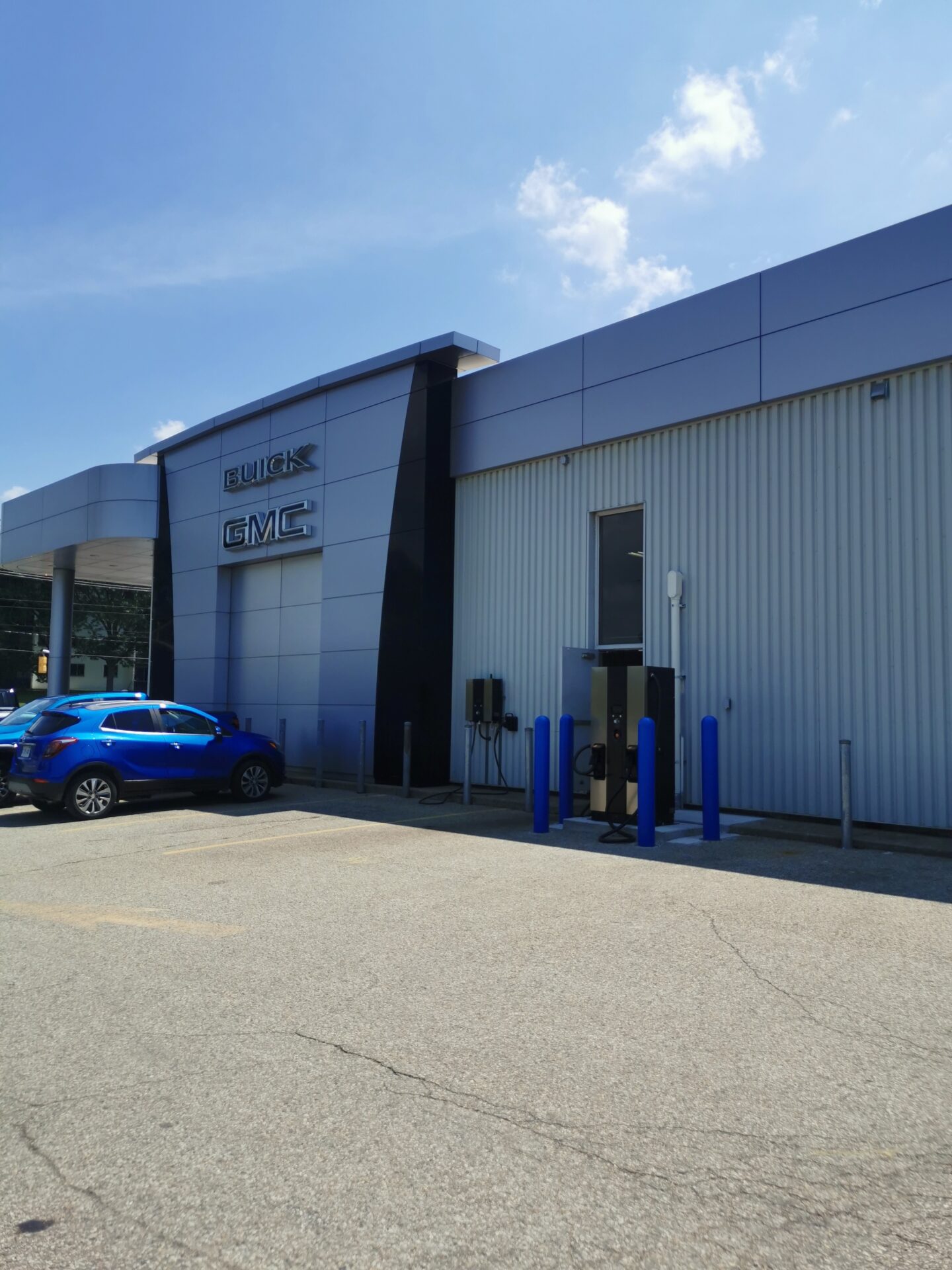 A car dealership with "Buick" and "GMC" signage, featuring a parked blue vehicle. The building is modern with a metal facade.