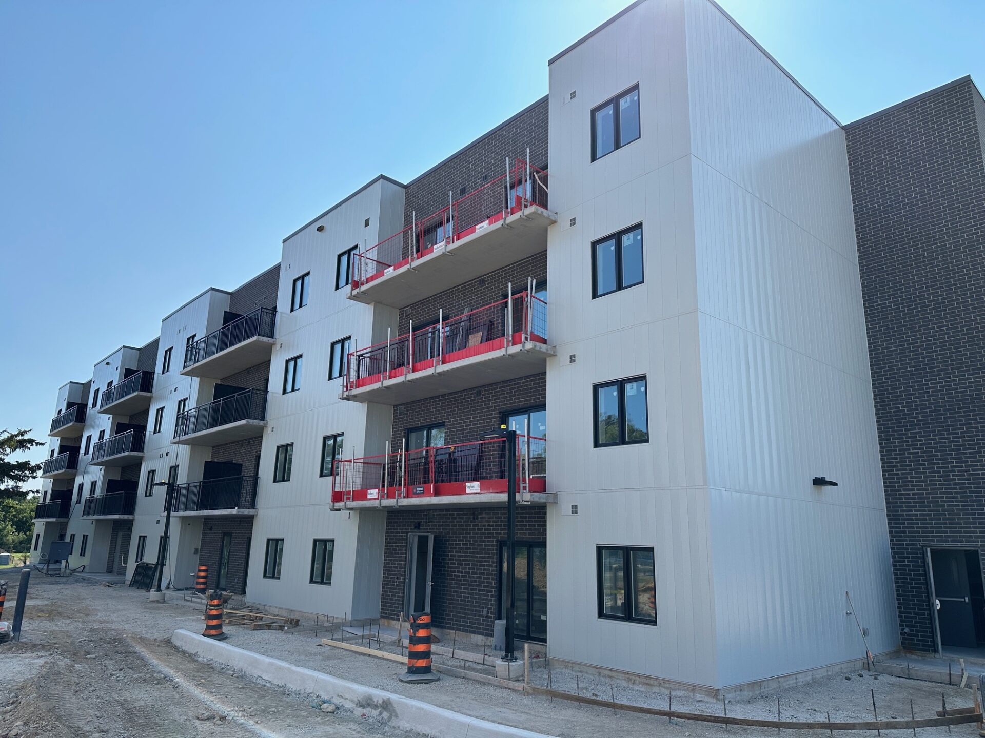 A newly constructed multi-story building with unfinished areas, surrounded by construction materials. Several balconies and windows are visible; no people are present.