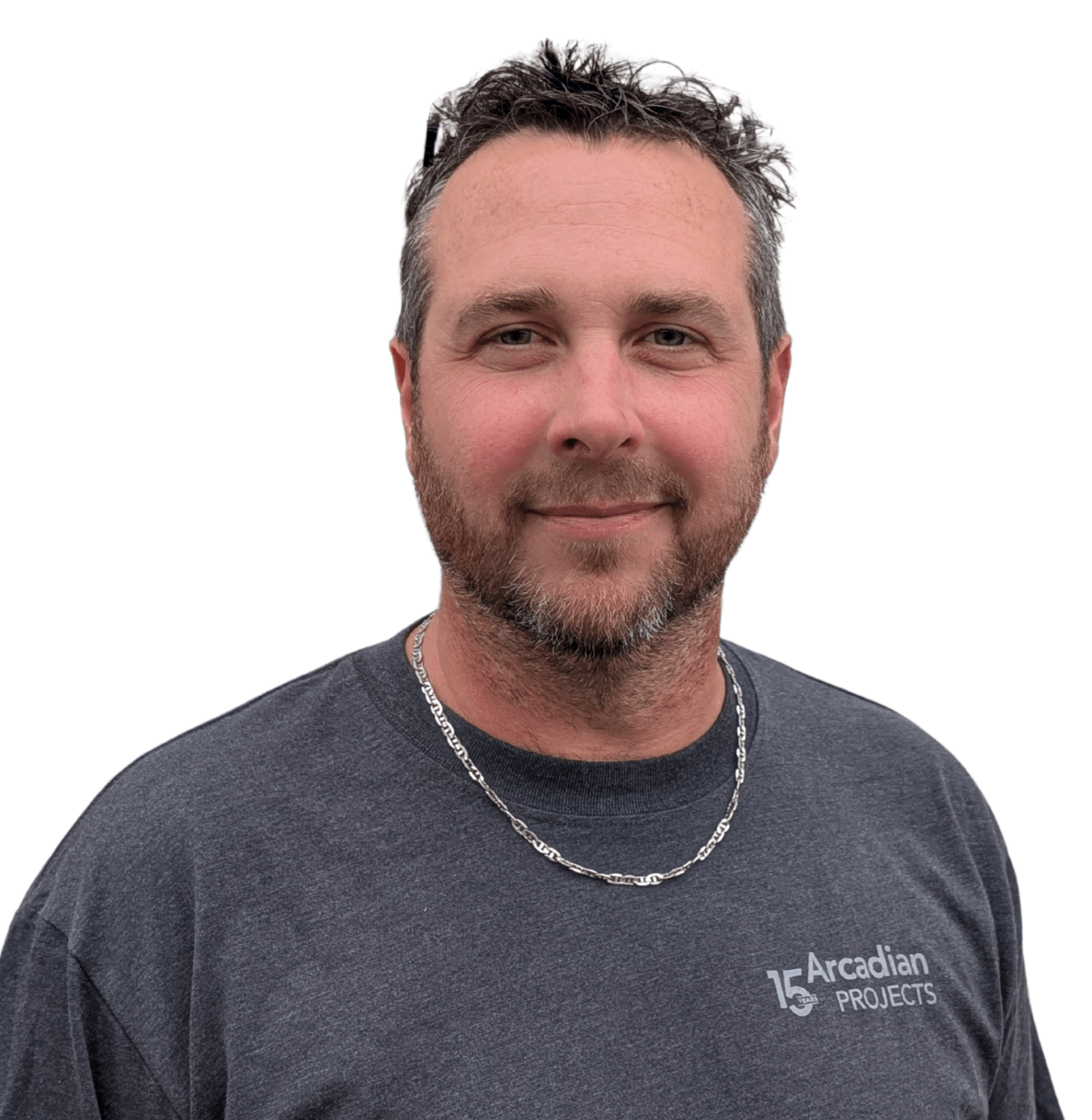 A person with short hair and a beard wearing a dark gray "Arcadian Projects" shirt, standing against a white background.